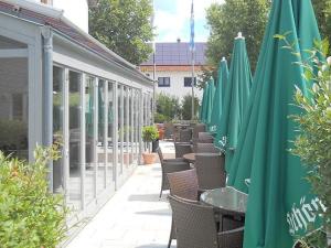 a row of tables and chairs with green umbrellas at Hotel Papillon in Lappersdorf +12 photos