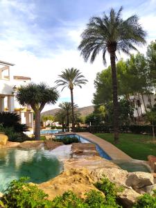 una piscina en un patio con palmeras en Apartamento Buganvilla Pool en Muntanya la Sella