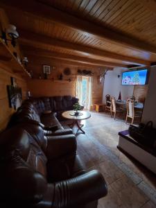 a living room with a leather couch and a tv at Chata Hrabovo in Ružomberok