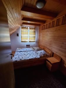 a bed in a wooden room with a window at Chata Hrabovo in Ružomberok