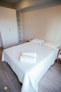 Un dormitorio con una cama blanca con toallas. en Cookandmusicapartments Forvm Molas López en Asunción