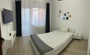 ein weißes Schlafzimmer mit einem Bett und einem TV in der Unterkunft Enjoy Apartment Barlad in Bîrlad