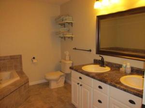 a bathroom with two sinks and a toilet and a mirror at Beulah Land Guest House w/King Bed & Jacuzzi Tub in Benzonia