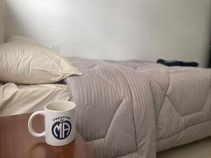 a coffee cup sitting on a table next to a bed at MBZ - Pleasant Stay in Abu Dhabi