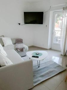 a living room with a white couch and a table at Charmante petite maison de ville avec balcon in Fréjus