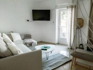 a living room with a white couch and a table at Charmante petite maison de ville avec balcon in Fréjus