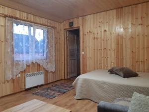 1 dormitorio con paredes de madera y 1 cama con ventana en Treimani Hoovimaja, en Treimani