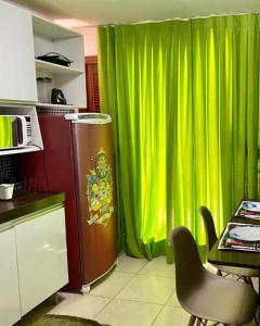 eine Küche mit einem grünen Vorhang und einem Tisch mit einem Stuhl in der Unterkunft Apartamento Studio - Solar Pipa in Pipa
