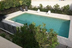 einen Pool mit zwei Stühlen neben einem Gebäude in der Unterkunft La maison d'Amélie, Villa climatisée piscine privée 4 Chambres, 3 sdb in Mazan