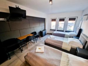 una camera con due letti, un tavolo e una televisione di Orange Tree Hotel a Będzin