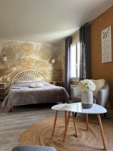 Schlafzimmer mit einem Bett und einem Tisch in der Unterkunft Le Bleu de B. in Saint-Étienne-en-Bresse