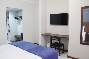 a bedroom with a bed and a desk and a tv at Days inn by Wyndham Uberlândia in Uberlândia