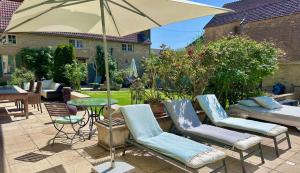 eine Terrasse mit 2 Stühlen und einem Tisch mit einem Sonnenschirm in der Unterkunft La Cour des Délices in Gigny