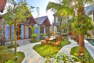 un jardin avec un banc en bois et des arbres dans l'établissement Tam Coc Serenity Hotel & Bungalow, à Ninh Binh