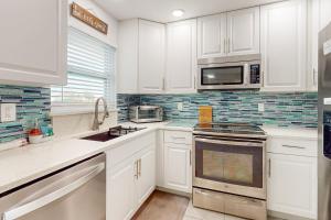 a kitchen with white cabinets and a sink and a microwave at Dreaming on the Canal in Port Charlotte
