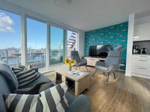 a living room with a couch and chairs and a television at Schwimmendes Haus am Pier in Olpenitz