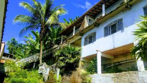 a house with palm trees in front of it at Beleza de Angra Apartamento Aconchegante in Angra dos Reis