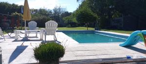 two chairs and a table next to a swimming pool at Comodidad y espacio para relax in Falda del Carmen