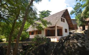 ein weißes Haus mit einem Felsen davor in der Unterkunft Eco Lodge Cristal Nosy Komba in Nosy Komba