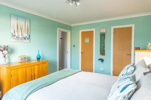 um quarto com paredes azuis, uma cama e uma cómoda em madeira em The Portwey Pearl em Rodwell