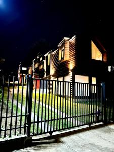 a fence in front of a house at night at AncudLodge in Ancud