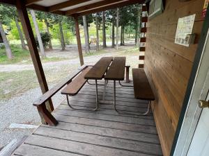 a picnic table and benches on a wooden porch at Nasu Takahara Auto Campsite - Vacation STAY 42066v in Nasushiobara