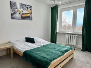 a bedroom with a bed with a green blanket on it at Apartament Stadion - duży apartament blisko Stadionu Narodowego w Warszawie. in Warsaw