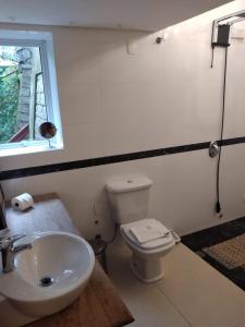 a bathroom with a toilet and a sink and a window at Loft em Caldas da Imperatriz - SC in Santo Amaro da Imperatriz