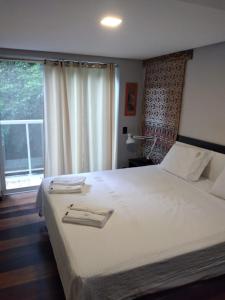 - une chambre avec un grand lit blanc et une fenêtre dans l'établissement Loft em Caldas da Imperatriz - SC, à Santo Amaro da Imperatriz
