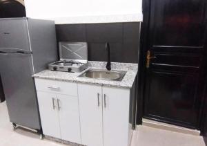 La cuisine est équipée d'un évier et d'un réfrigérateur noir. dans l'établissement DAR IJLAL, à Marrakech