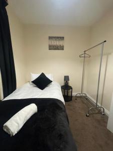 Spacious 4-bed House in Leicester في ليستر: غرفة نوم بسرير اسود وبيض ومصباح