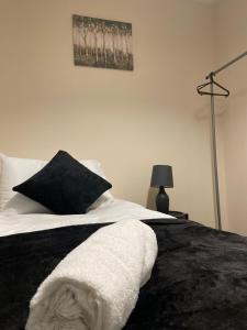 Spacious 4-bed House in Leicester في ليستر: سرير وبطانية بيضاء وسوداء ومصباح