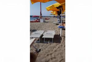 una fila di sedie a sdraio e ombrelloni in spiaggia di Sabrina Airport a Fiumicino