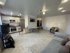 uma sala de estar com um sofá e uma cozinha em Трехкомнатная квартира в центре города с выходом в центральный Парк em Qostanay
