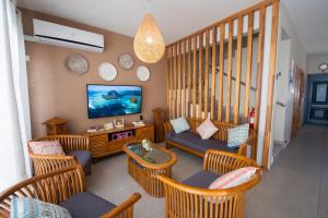een woonkamer met rieten stoelen en een flatscreen-tv bij Golden Square Villa & Private Pool in Flic-en-Flac