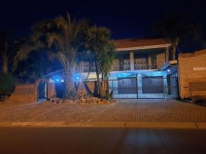 a house with a fence and palm trees at night at Gae la boroko @legodi's in Brakpan