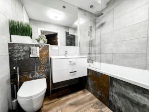 a bathroom with a white toilet and a sink at Apartament 101 Kępa Mieszczańska in Wrocław