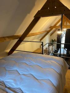 a white bed in a room with an attic at Gastenverblijf A&A met mezzanine in Gavere