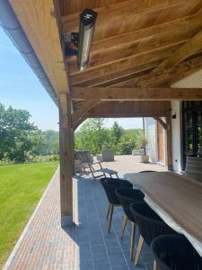 un patio con una mesa larga y sillas bajo un techo de madera en Gastenverblijf A&A met mezzanine en Gavere