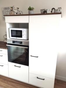 a white cabinet with a microwave and a microwave oven at ARBI'ZEN ,appartement Bagnères de Bigorre, domaine golf de la Bigorre, vue exceptionnelle sur la chaine des Pyrénées in Bagnères-de-Bigorre