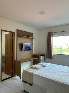 1 dormitorio con 1 cama y TV en la pared en Hotel Carvalho, en Ibiapina