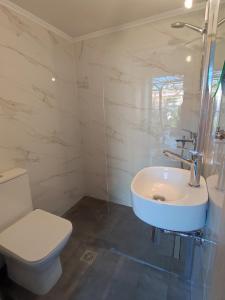 a white bathroom with a toilet and a sink at Nicola's House in Myrina