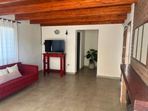 een woonkamer met een rode bank en een tv bij Balcón al río in Villa Carlos Paz