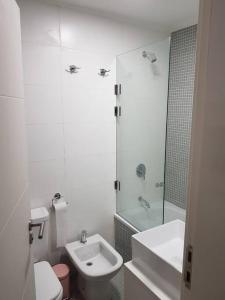 La salle de bains blanche est pourvue de toilettes et d'un lavabo. dans l'établissement Departamentos en Uruguay al río, Dos Orillas, Dazzler, Colonia, à Colonia del Sacramento