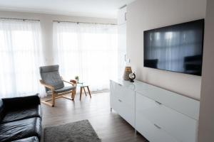 a living room with a tv on a white dresser at Moderne Wohnung mit großer Terrasse in erster Reihe am Deich, Wallbox, Kajak in Schönberger Strand