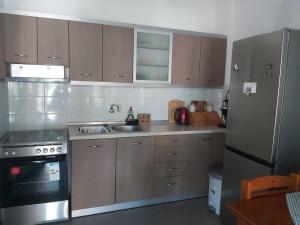 a kitchen with wooden cabinets and a stainless steel refrigerator at Nicola's House in Myrina