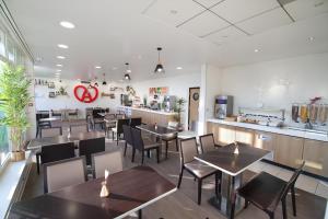a restaurant with tables and chairs and a counter at Holiday Inn Express Strasbourg - Sud, an IHG Hotel in Geispolsheim