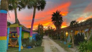 a sunset over a resort with a playground and palm trees at The Beach House at Si Como No Inn in Flagler Beach