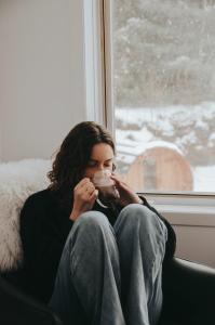 a woman sitting on a window sill drinking a drink at Suite 110 - Destination Mont-Orford in Magog-Orford