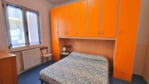 a bedroom with orange cabinets and a bed and a window at MARZIO - appartamenti con terrazzo, posto auto e spiaggia in Marcelli